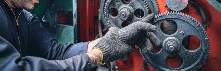Industrial worker operating heavy machinery in Greensboro factory, highlighting risks of workplace accidents