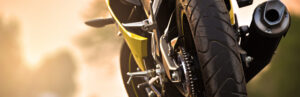 picture of the lower half of a motorcycle facing the opposite direction in front of a blurry dirt background