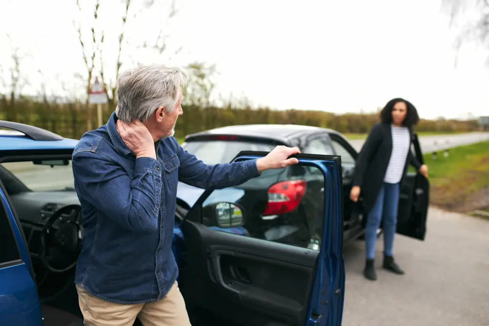 man rubbing his neck after car accident