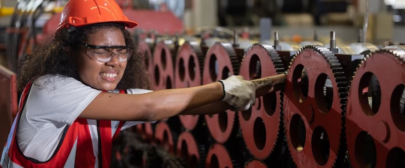 Female worker in safety vest and hard hat operating machinery.