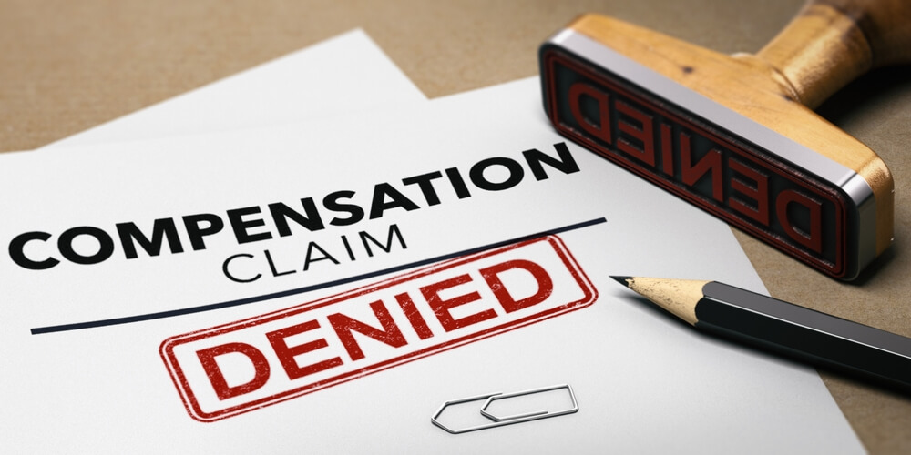 Workers’ compensation claim denial notice with stamp and paperwork in Greensboro