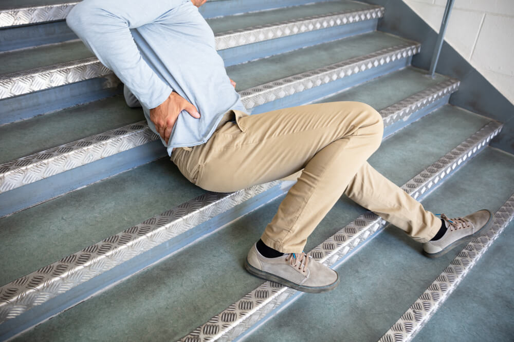 Injured man on stairs after fall – Greensboro slip and fall attorney can help with premises liability claims.