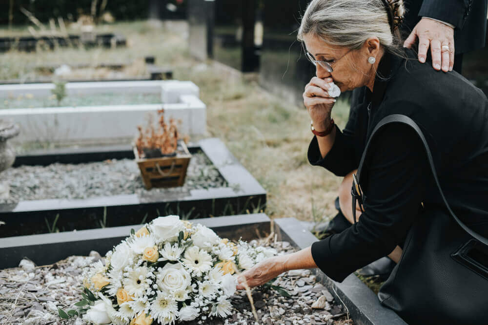 Grieving woman at a gravesite after wrongful death, symbolizing loss and seeking justice with a Greensboro wrongful death lawyer