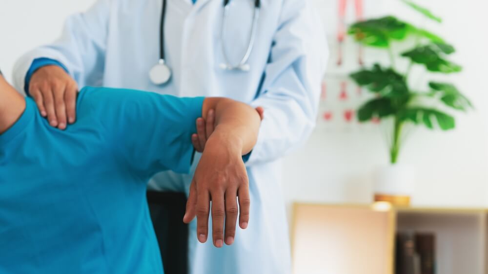 Doctor examining a worker's shoulder injury during a medical evaluation in Greensboro, NC